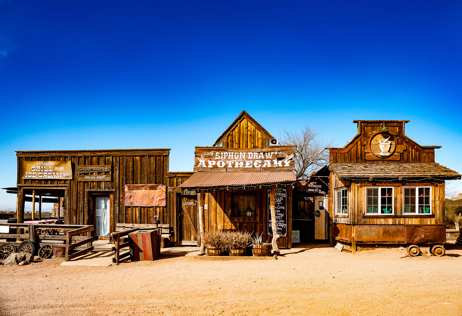 Rustic Old West storefronts at Goldfield Ghost Town featuring wooden facades, desert landscape, and authentic Western vibes.