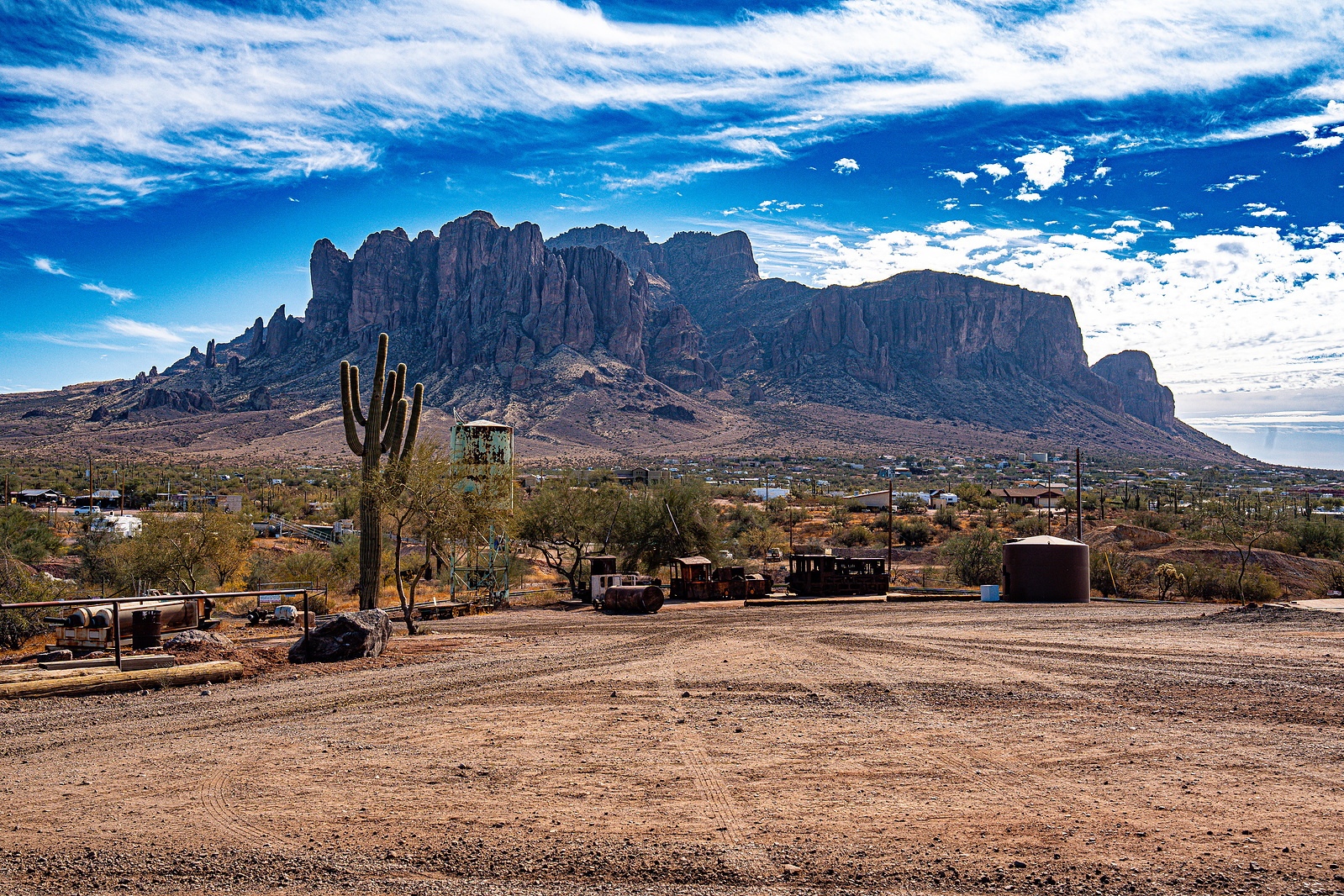 Desert landscape view of the Superstition Mountains and tall cacti at Goldfield Ghost Town in Arizona.