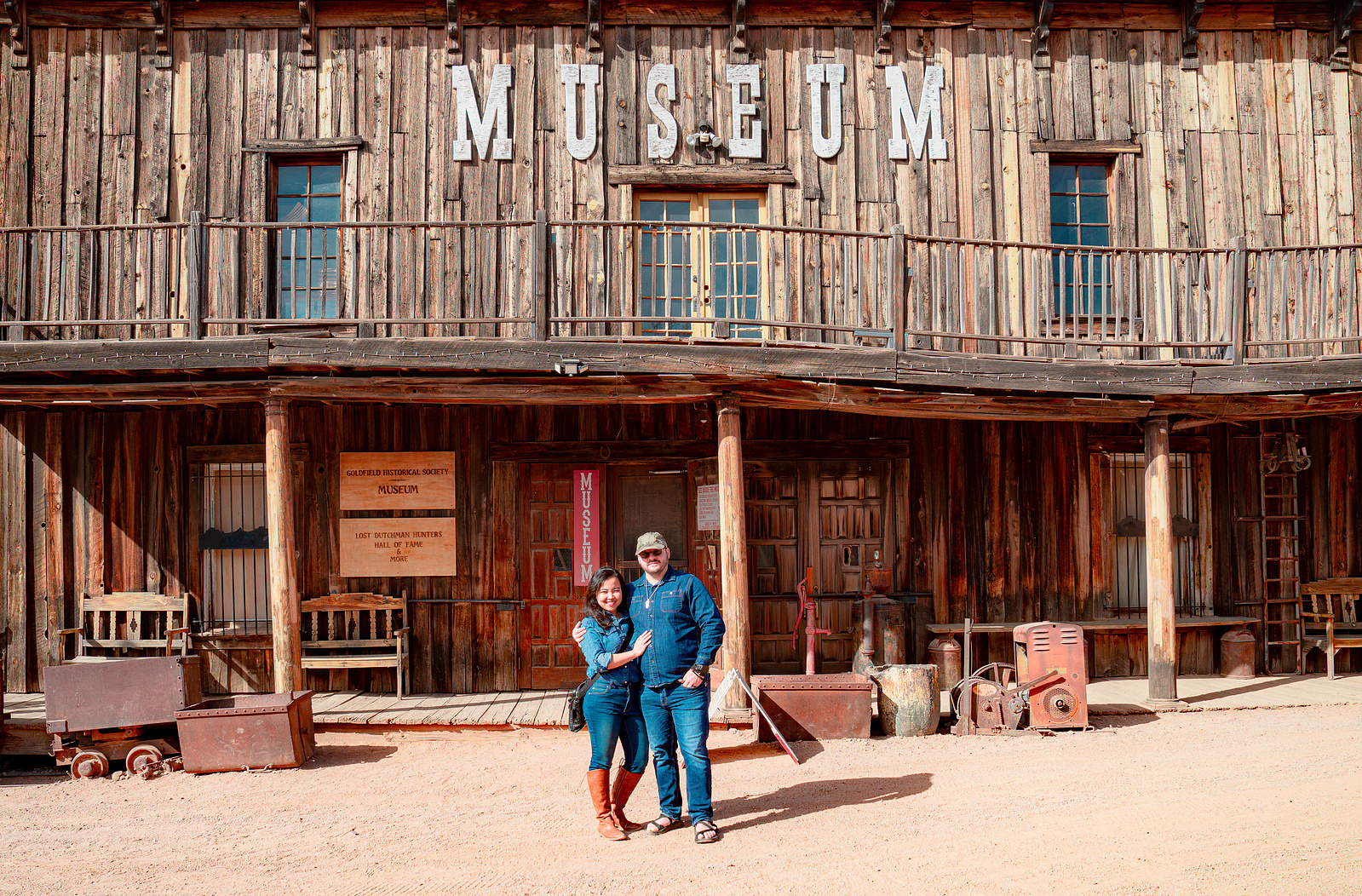 Visitors posing outside the Goldfield Museum, a historic Old West building in Arizona.