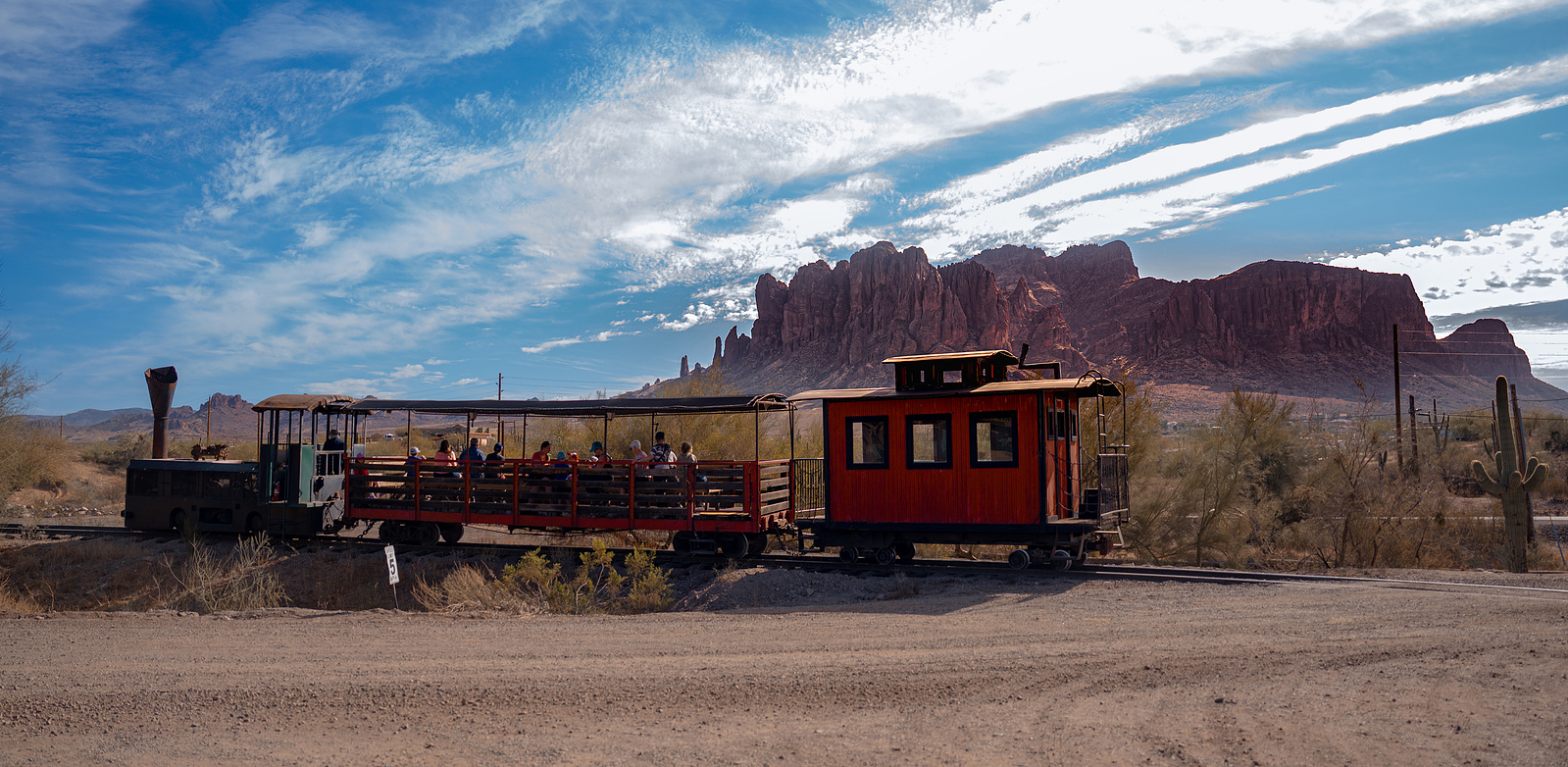 Vintage red train car at Goldfield Ghost Town with Superstition Mountains in the background, a scenic Arizona desert photography location.
