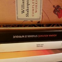 close up of the pile of books, and the ankara on the spine of the text block can just be seen pressed in between two of them.