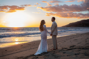 A couple walking on the beach hand in hand at sunset.