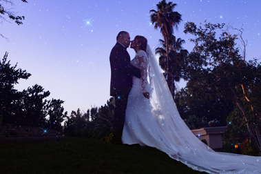 Bride and groom embrace beneath the evening sky.