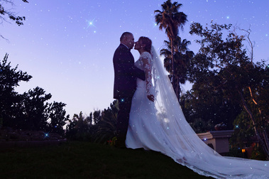 Bride and groom embrace beneath the evening sky.