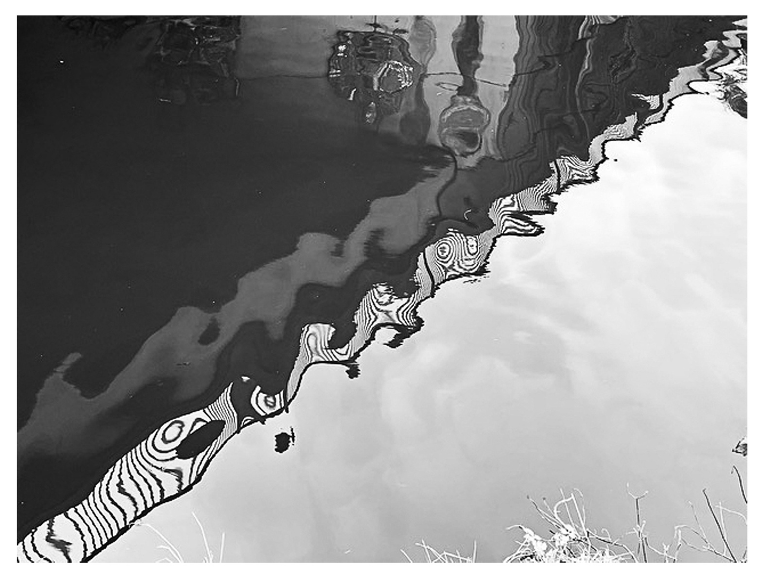 Black and white refection in water of a fence and walk way