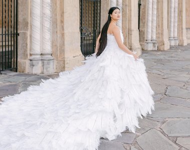 chinese bride wears white ostrich feather wedding dress while running past a castle gate