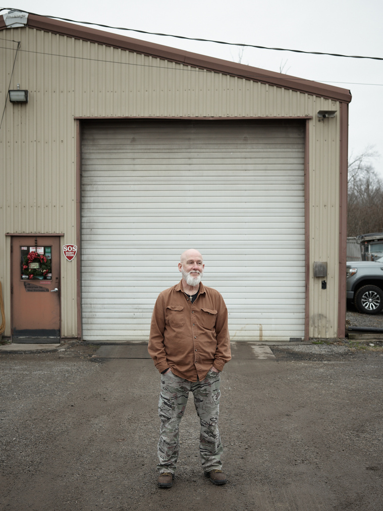 Semi-truck mechanic standing outside of garage.