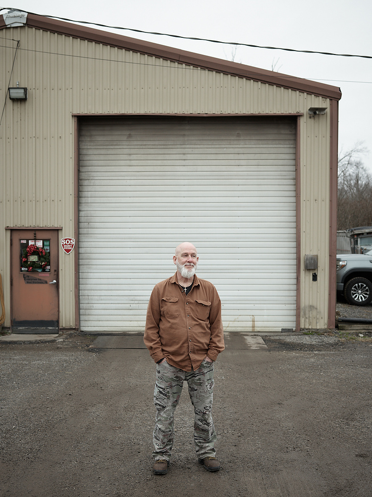 Semi-truck mechanic standing outside of garage.