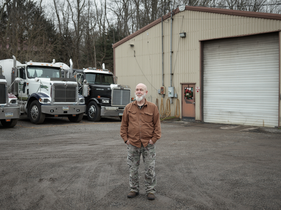 Trucking mechanic stands outside of his garage.