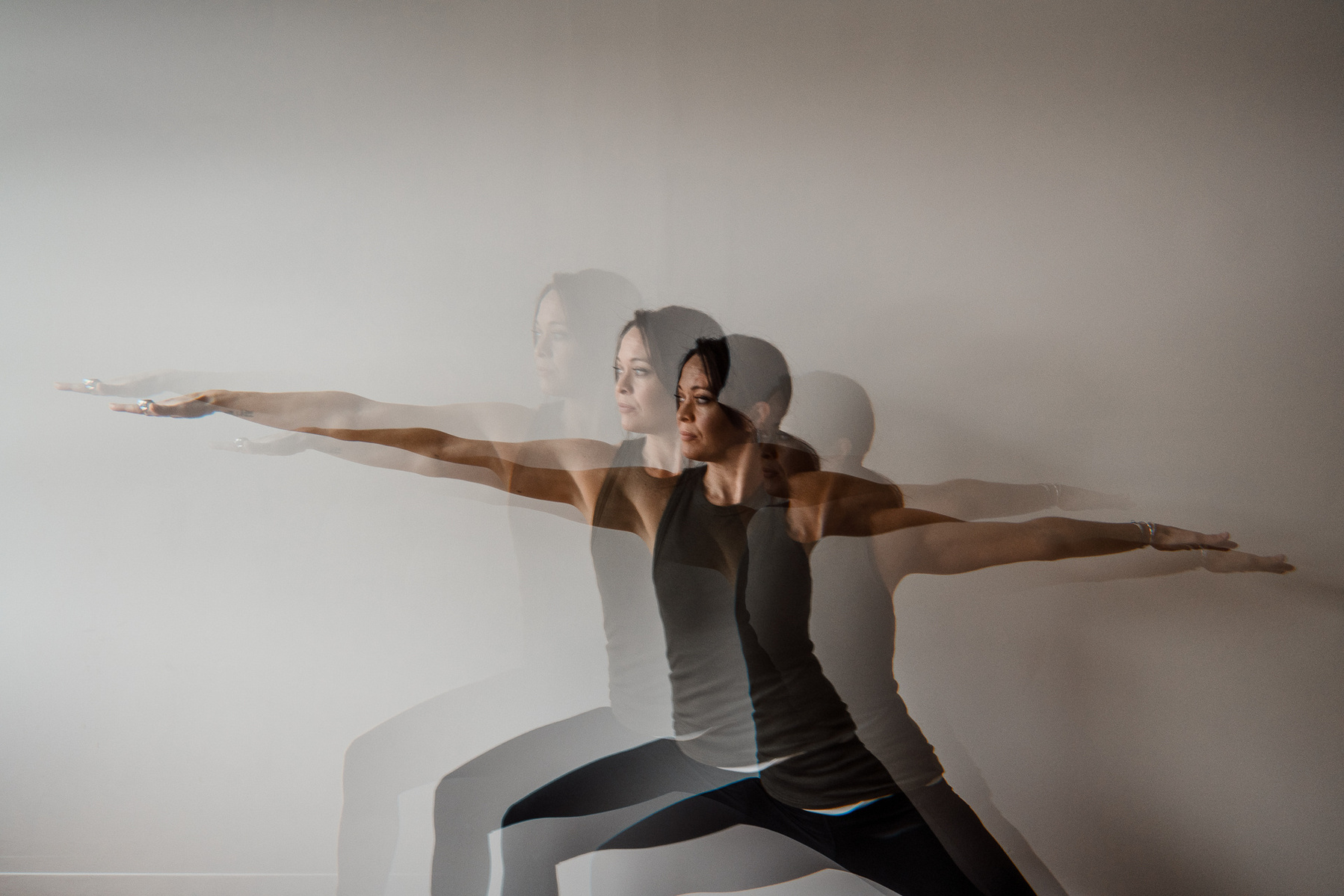 Yoga teacher Jill Barry in warrior 2 pose against a white wall in the Norwood photography studio of Boston yoga photographer Korri Leigh Photography