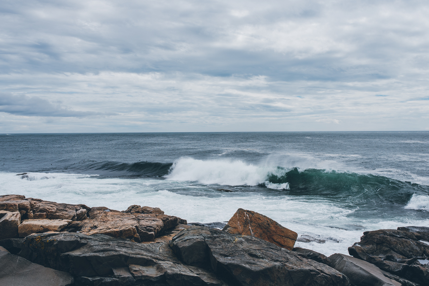 A wave approaches the rocky Maine coast in Acadia National Park taken by Boston landscape photographer Korri Leigh Crowley