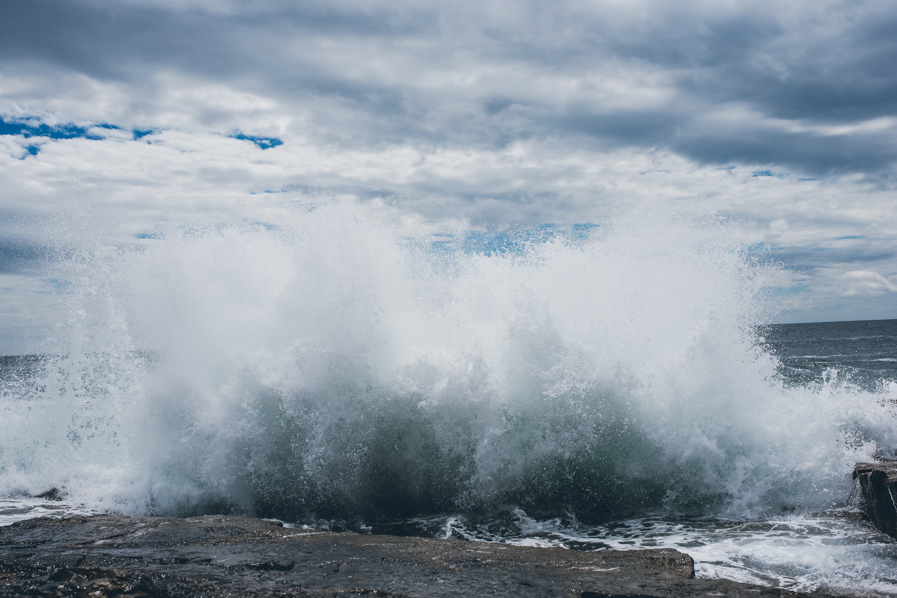 A wave crashes along the rocky Maine coast in Acadia National Park taken by Boston landscape photographer Korri Leigh Crowley