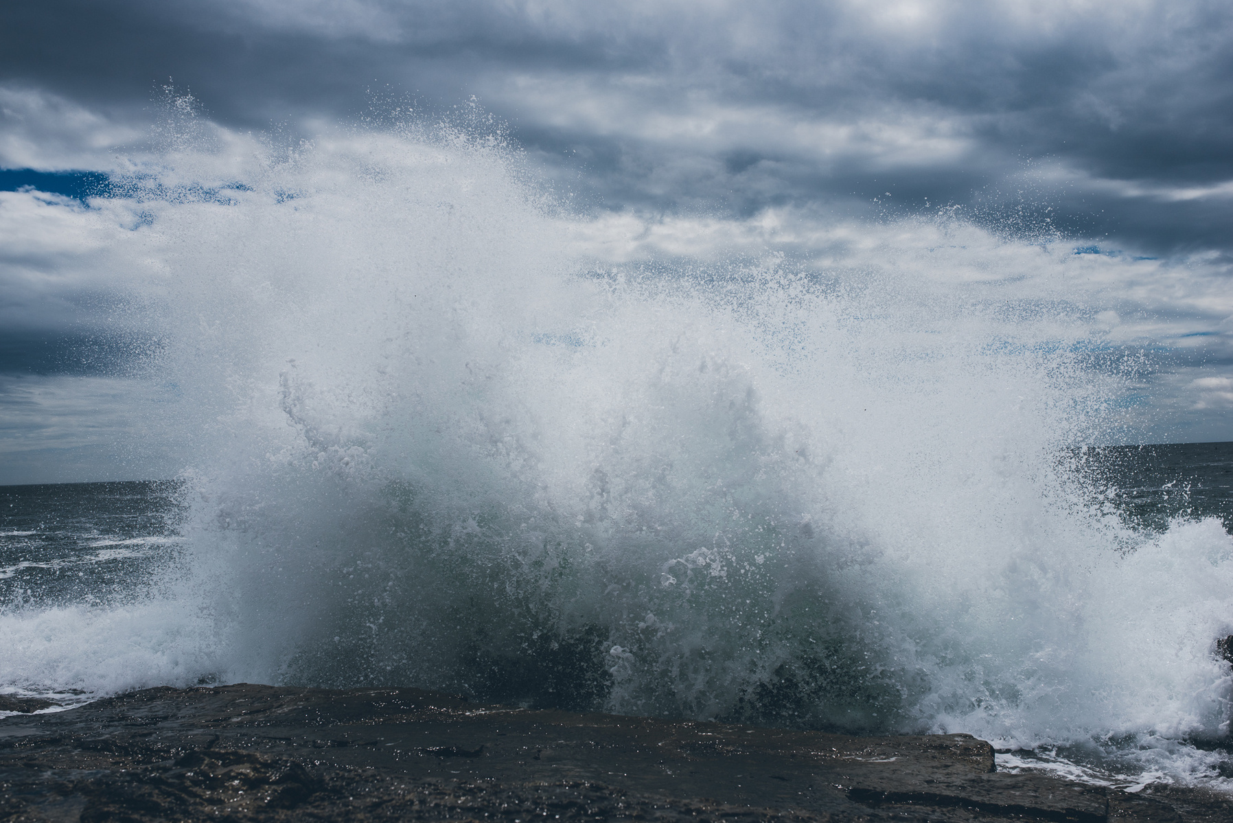 A wave crashes along the rocky Maine coast in Acadia National Park taken by Boston landscape photographer Korri Leigh Crowley