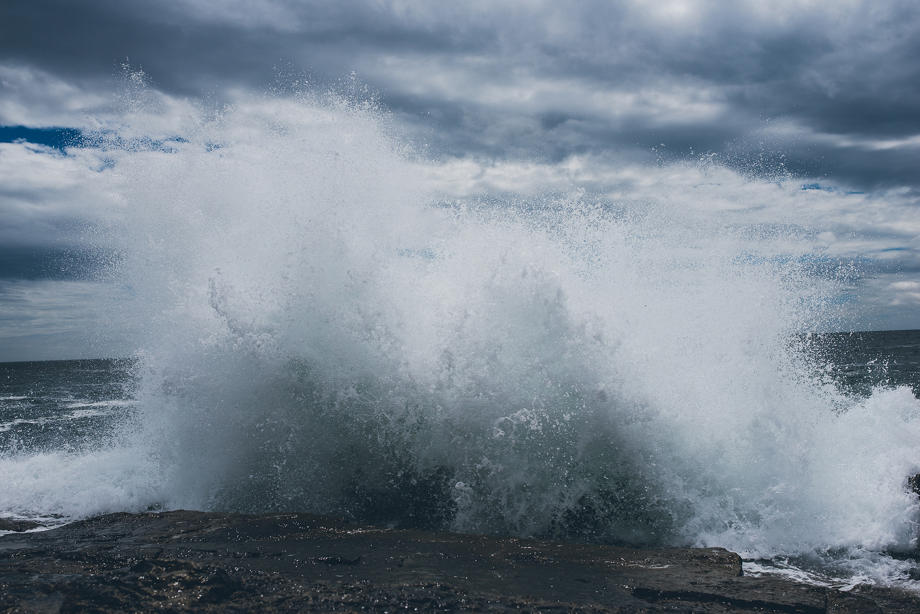 A wave crashes along the rocky Maine coast in Acadia National Park taken by Boston landscape photographer Korri Leigh Crowley