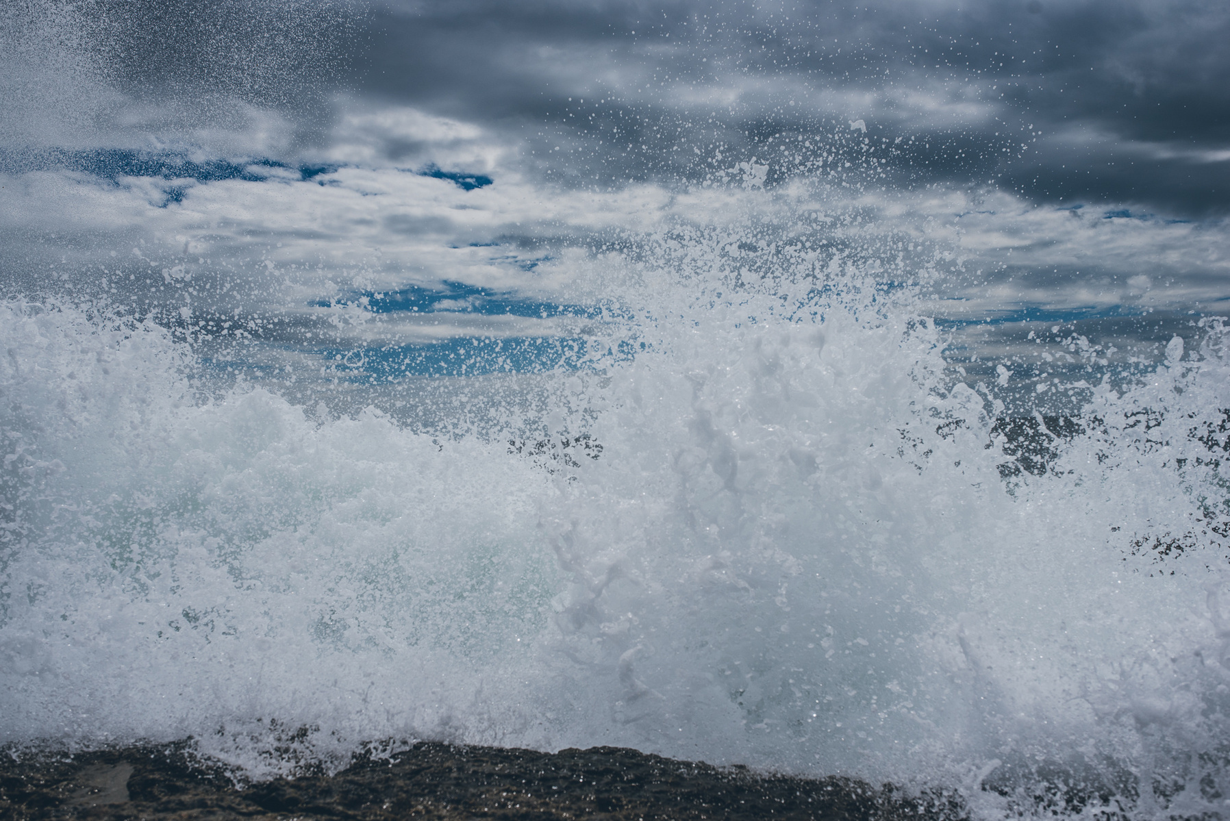 A wave crashes along the rocky Maine coast in Acadia National Park taken by Boston landscape photographer Korri Leigh Crowley