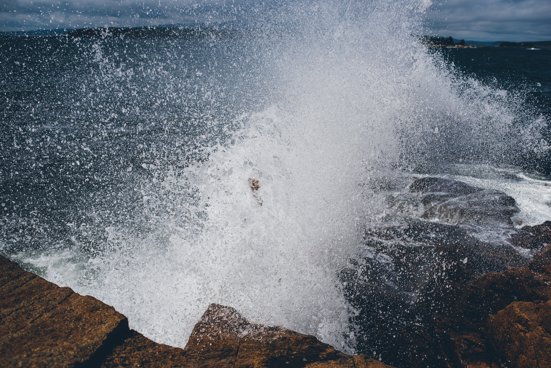 A wave crashes along the rocky Maine coast in Acadia National Park taken by Boston landscape photographer Korri Leigh Crowley