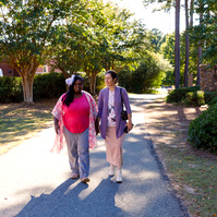 Mother and daughter walk outside on a sunny day. 