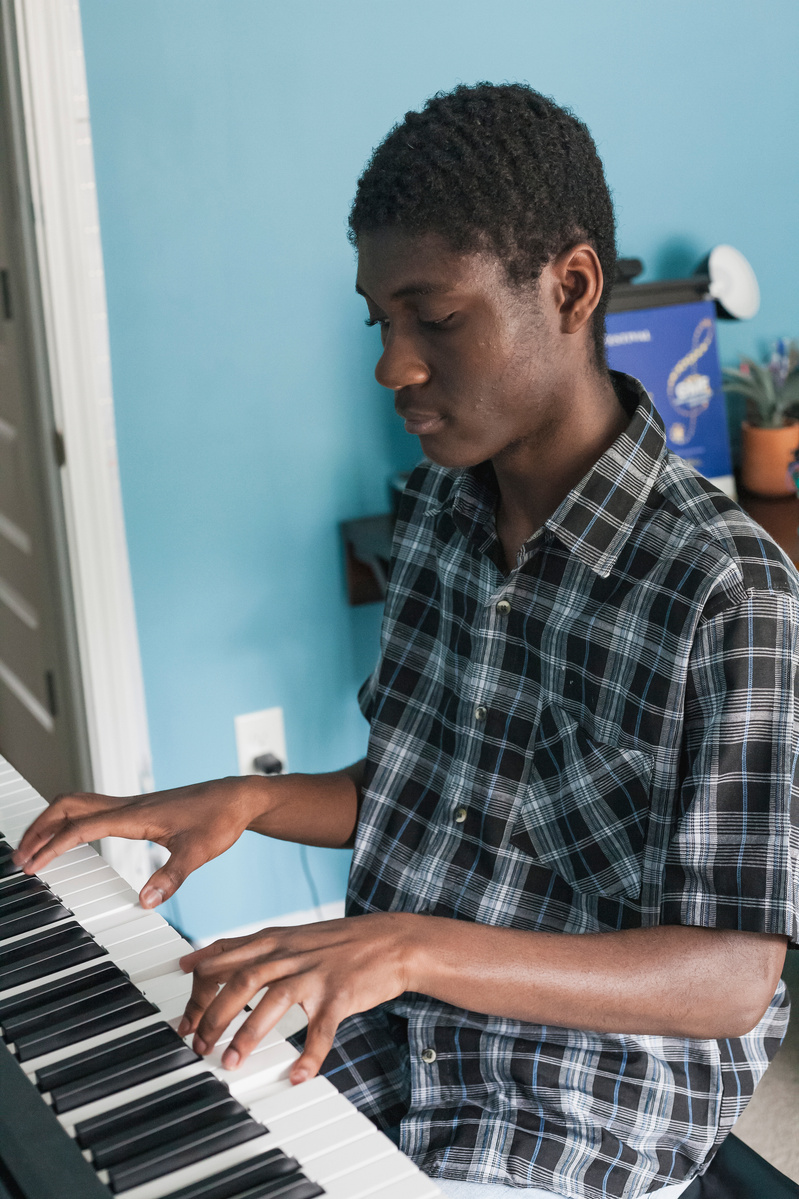 A young African American man plays the piano.