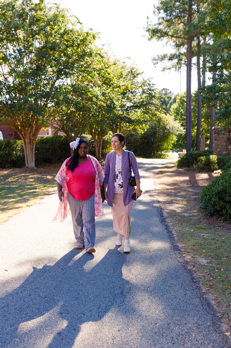 Mother and daughter walk outside on a sunny day. 