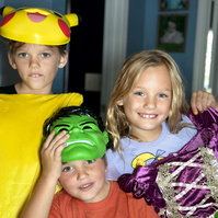 Three children in costumes smile for the camera. 