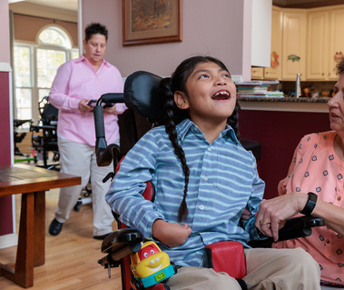A young boy smiles as his mother holds his hand. 