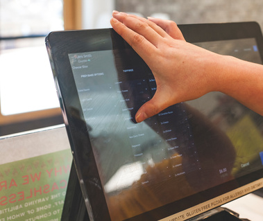 A hand types on an electric cash register. 