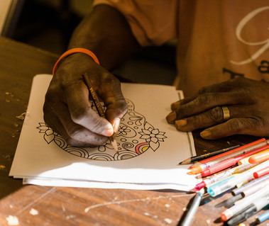 A hand draws and colors using pens.