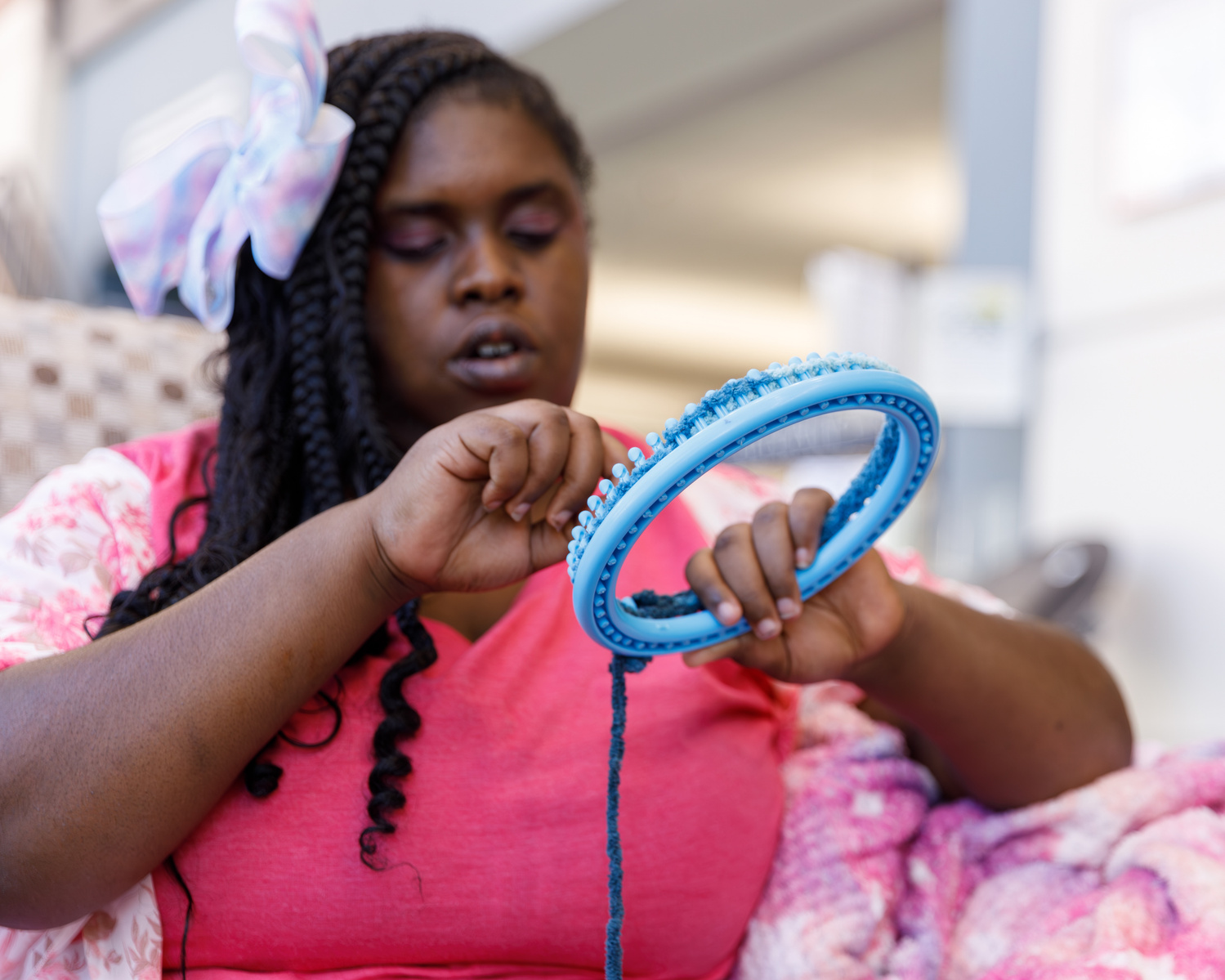 A young African American woman uses a circle loom with yarn.