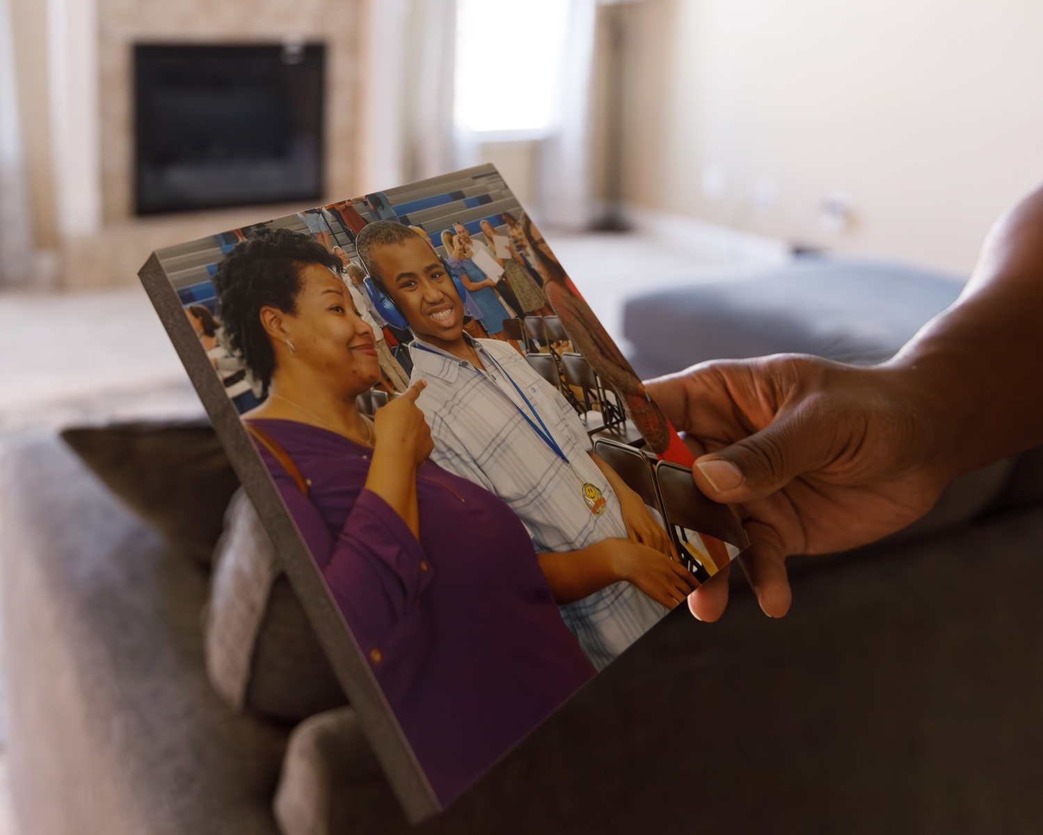 The hands of an African American man hold a photo of a woman and a young man. 