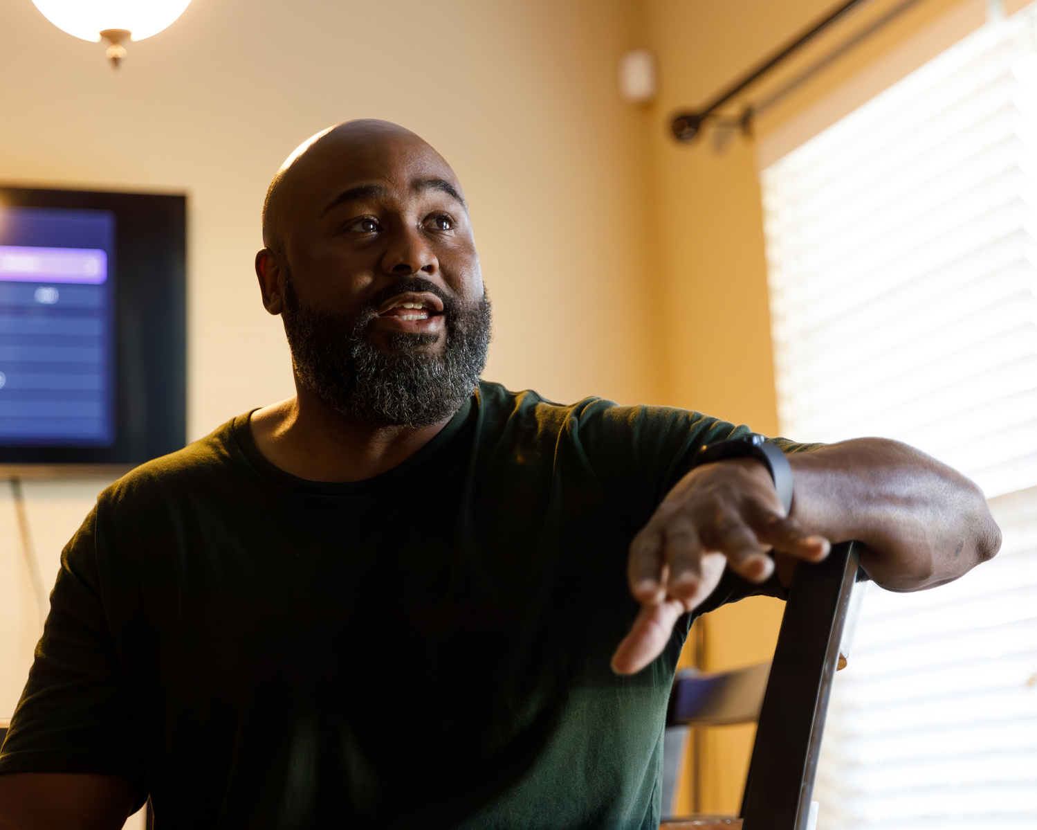 Bald African American man sits in a chair. 