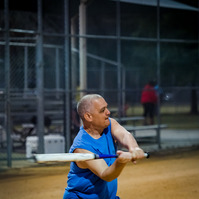A man in a blue shirt hits a baseball with a bat.