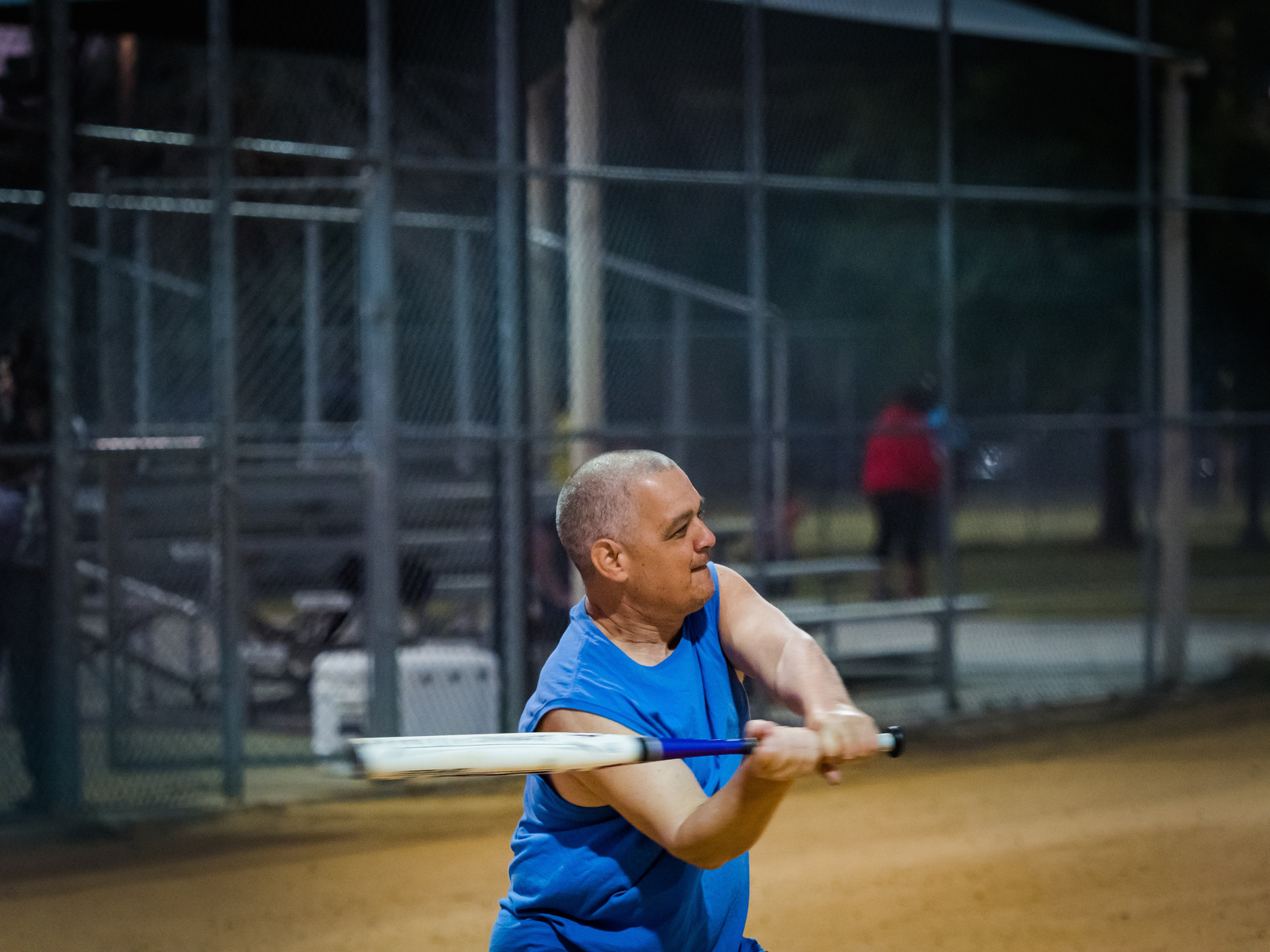 A man in a blue shirt hits a baseball with a bat.
