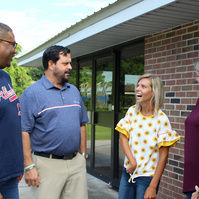 Five people stand in front of a brick building and talk. 