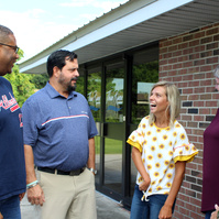 Five people stand in front of a brick building and talk. 