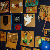 Pieces of Dream Weaver artwork hangs on a dark blue wall.