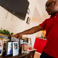 A father wears a red shirt as he proudly looks at family photos. 