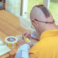 Man in yellow shirt places label on bag of popcorn.