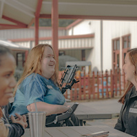 Four women sit at a table and talk to each other. 