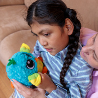 A boy with two long braids sits in his mother's lap and hols a toy.