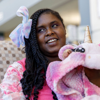 Young African American woman sits on a sofa with a stuffed unicorn