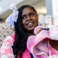 Young African American woman sits on a sofa with a stuffed unicorn