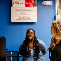 Young African American woman wears braids and talks to one of her instructors. 