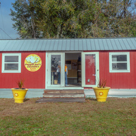 A red one story building sits with a green lawn in front of it.