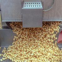 Popcorn pours out of a metal machine.