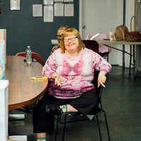 Dream Weaver member sits at a table wearing a pink shirt.