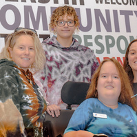 A group of four women pose in front of a sign that reads community responsibility.