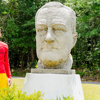 A young African American male stands next to a large sculpture of President Roosevelt.