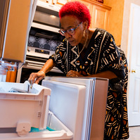 A woman with red hair looks into her refrigerator. 