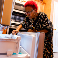 A woman with red hair looks into her refrigerator. 