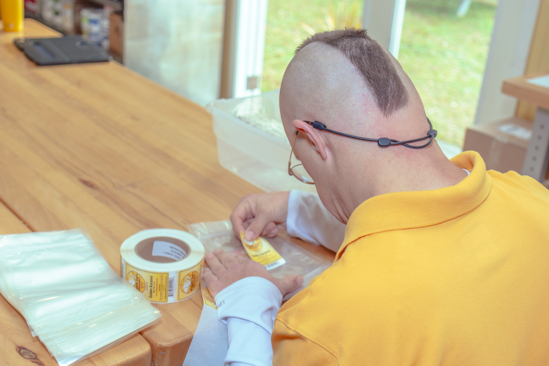 Man in yellow shirt places label on bag of popcorn.
